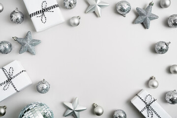Christmas presents, various silver ornaments on light grey background. Gifts wrapped in white paper and decorations. Festive monochrome composition. New year mockup. Flat lay, top view, copy space.