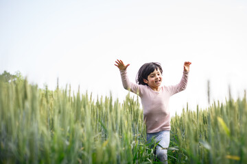 close view of girl with short hair in pink top run happily in wheat field