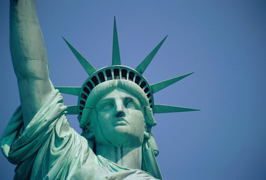 Close view of the Statue of Liberty's face against a bright blue sky on a sunny day; New York City, New York, United States of America