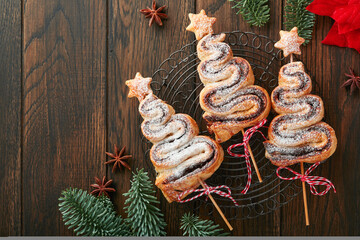 Christmas tree shape puff pastry cakes with chocolate filling, sugar powder and lollipops on old wooden background. Christmas, New Year Appetizer. Festive idea for Christmas or New Year dinner.