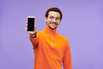 Young cheerful man in casualwear showing smartphone with blank screen for your advert, sale...
