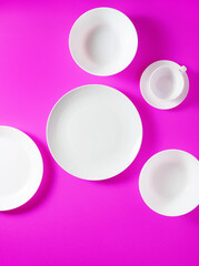 a set of white dishes on a bright violet background. taken from above