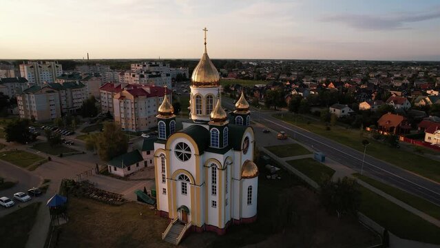 Aerial view of beautiful orthodox church with crosses on golden domes and new microdistrict with infrastructure