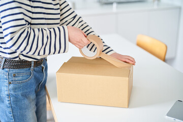 段ボールに荷物を詰める若い女性