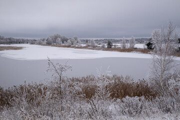 Anes karjers pond near Jelgava town in Latvia. Freezing overcast winter day. snow and ice covered...
