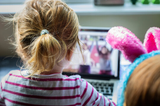 Two red headed girls sitting in front of a lap top screen.
