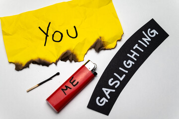 Word Gaslighting, on a black surface, next to a lighter with the word Me, and burnt yellow card with the writing You. Psychological meaning. - obrazy, fototapety, plakaty