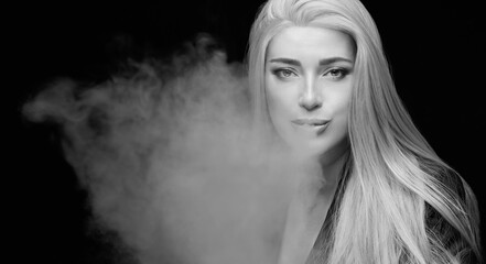 Beautiful sexy woman blowing smoke. Monochrome studio portrait isolated on black
