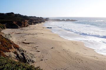 Coast of the Pacific ocean beach with cliffs, rocks, sand and waves