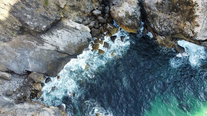 Aerial top view of turquoise waves of Atlantic ocean breaking on the rocks on Ursa Beach (Praia da ursa), Portugal