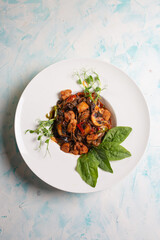 top view of a warm salad with mushrooms and meat, cheese and sauce in a white plate