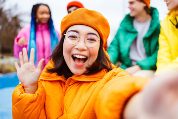 Multiracial group of young happy friends wearing colorful winter jackets meeting outdoors in...