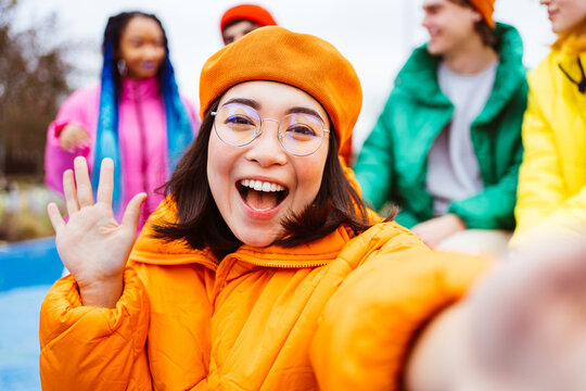Multiracial group of young happy friends wearing colorful winter jackets meeting outdoors in winter, concepts about youth generation, millennials, teenage and students social gathering - Powered by Adobe