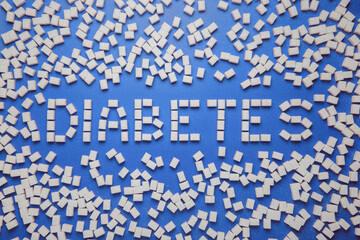 Diabetes word and a frame made from sugar cubes on blue background