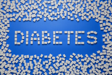Diabetes word and a frame made from sugar cubes on blue background