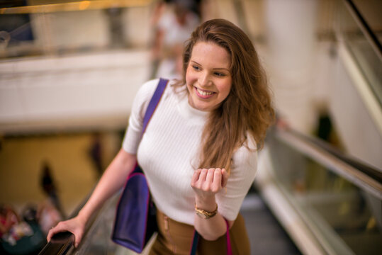 A young woman riding the escalator in a shopping mall.
