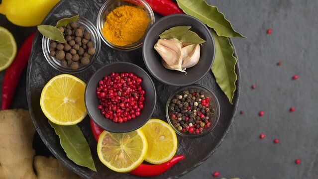 Set of Spices and herbs for cooking. Small bowls with colorful seasonings and spices - basil, pepper, saffron, salt, paprika, turmeric. On black stone table top view copy space