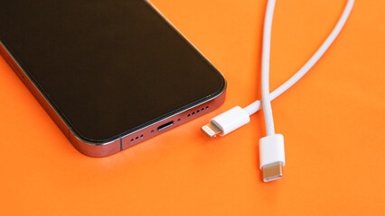 USB type C port cable for charging to the smartphone on orange background. EU law to force USB-C...