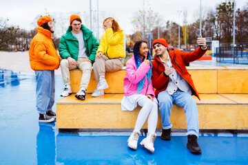 Multiracial group of young happy friends wearing colorful winter jackets meeting outdoors in winter, concepts about youth generation, millennials, teenage and students social gathering