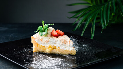 Piece of cake with meringue, fresh strawberries and mint.
