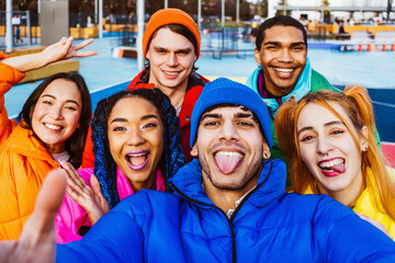 Multiracial group of young happy friends wearing colorful winter jackets meeting outdoors in winter, concepts about youth generation, millennials, teenage and students social gathering