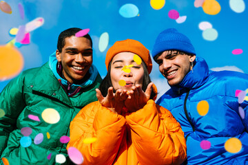 Multiracial group of young happy friends meeting outdoors in winter and celebrating party with...