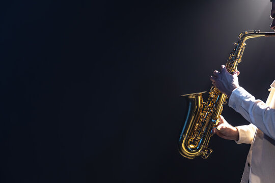 Saxophone in the hands of a man on a dark background, copy space.