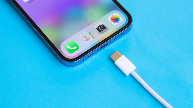 USB type C port cable for charging to the smartphone on blue background. EU law to force USB-C chargers. 