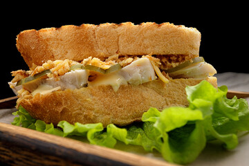 Sandwich with meat, cheese and cucumber on a wooden board