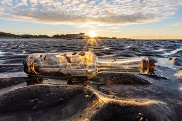 bottle post in the Wadden Sea at sunset - obrazy, fototapety, plakaty