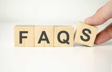 Businessman puts wooden blocks with the word FAQ frequently asked questions