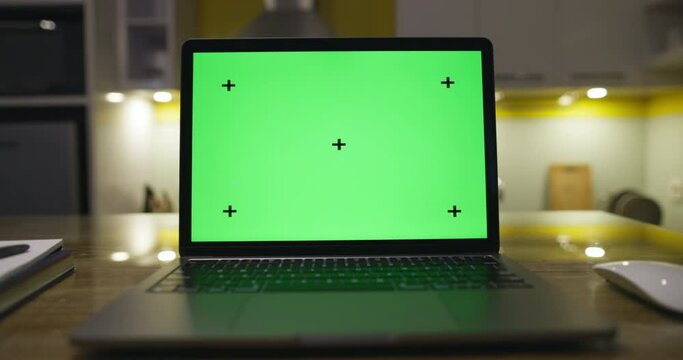 Modern laptop with blank green screen. dolly footage . Home interior modern kitchen background.Perfect to put your own image or video. Track points with perspective corner pin