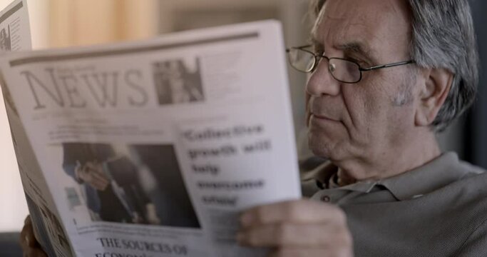 Old man reading the newspaper at home