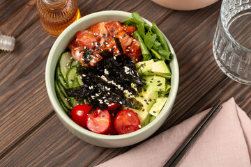 Poke bowl with red fish, avocado, spinach, cucumber and cherry tomatoes