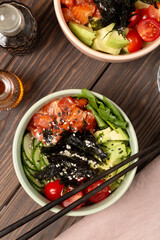 Poke bowl with red fish, avocado, spinach, cucumber and cherry tomatoes