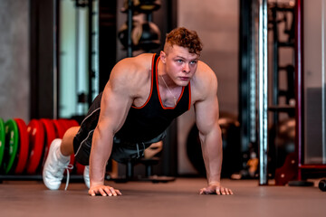 Fototapeta premium young athlete performs push-ups on the floor in the gym