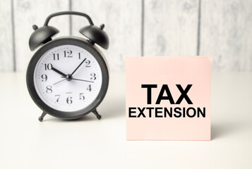 The word TAX EXTENSION written on pink sticker and alarm clock