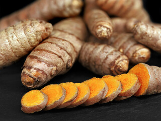 close up of sliced turmeric roots, Curcuma longa on black slate board