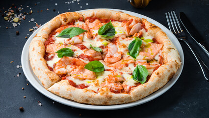 Italian pizza with shrimp, salmon, mozzarella, tomato sauce, basil on a thick dough with spices.