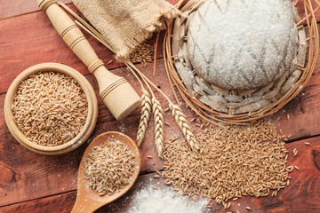 Wheat ears, sack with grain on a wooden light background. Round whole grain bread. Rolling pin, eggs, flour - ingredients for making bread. The concept of farming, natural products.