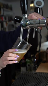 Bartender pours beer from tap into glass