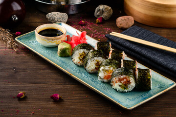 Set of sushi rolls with salmon, tobiko caviar, lettuce, wasabi, ginger and soy sauce.
