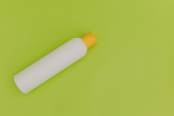 Shampoo for hair in a white package with a yellow cap on a green background