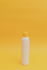 Shampoo for hair in a white package with a yellow cap on a yellow background, monochrome
