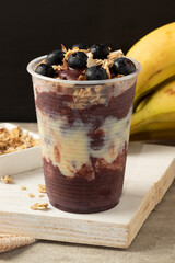 Frozen açaí with condensed milk, granola and blueberry in a plastic cup.