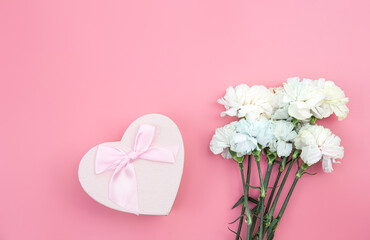 Bouquet of flowers, heart shaped gift box on pink background, flat lay.