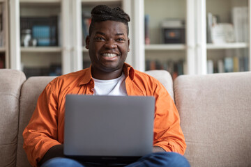 Positive african american man freelancer working from home, using laptop