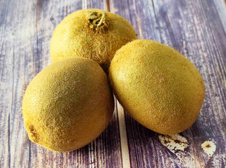 Three whole kiwi fruit on a wooden table. Close up 