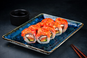 Set of Japanese maki sushi rolls with tuna tartare, salmon, crab sticks, cream cheese, avocado, red flying fish caviar and soy sauce.