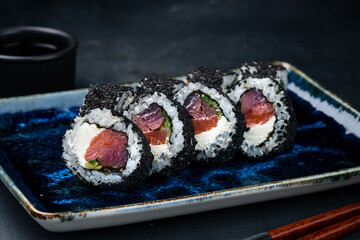 Set of sushi rolls with tuna, cream cheese, cucumber, sesame seeds and soy sauce.